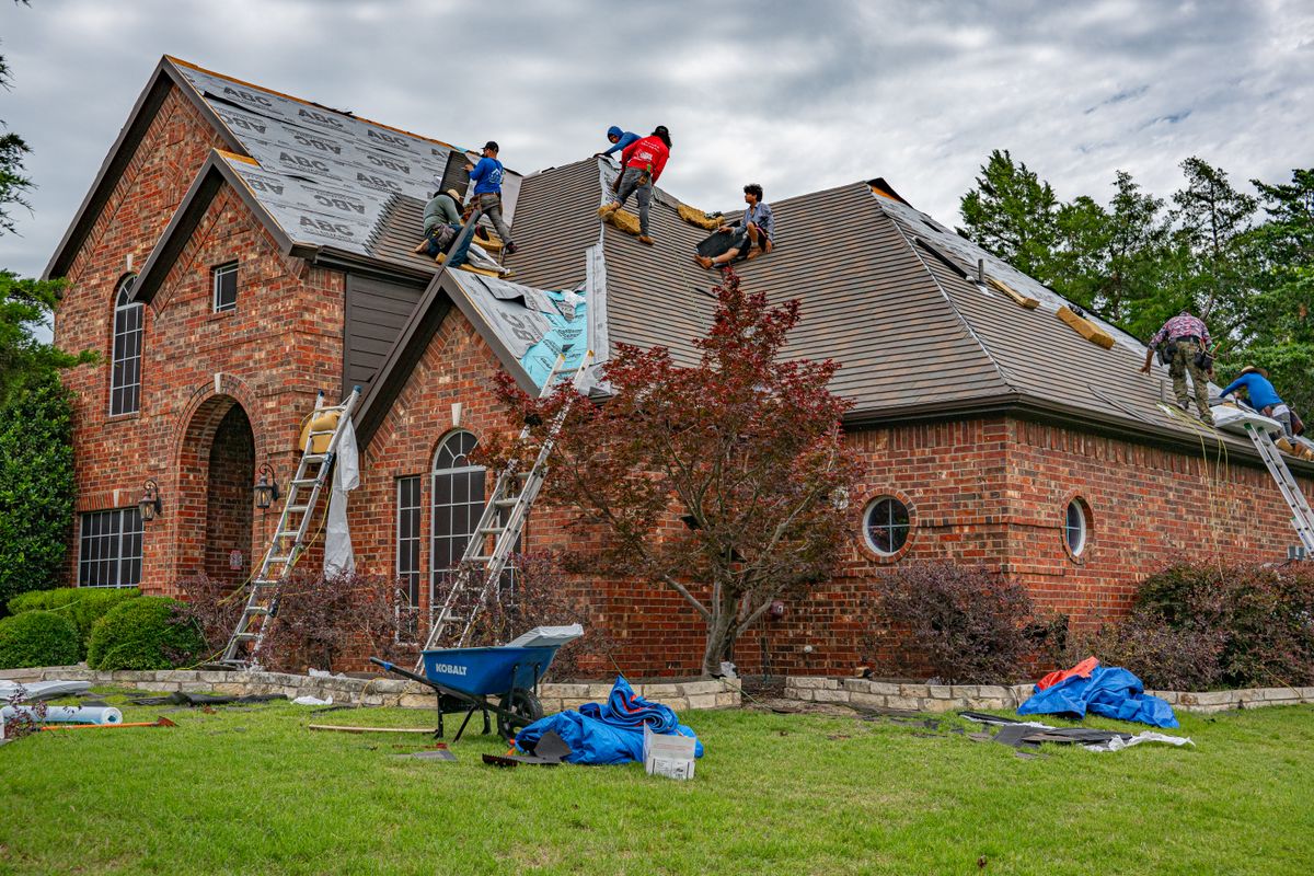 Roofing crew installing shingles on a brick home