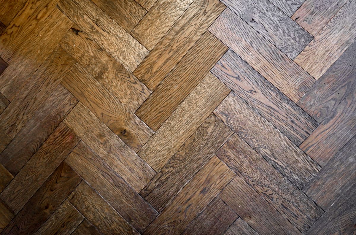 Herringbone wood floor pattern in warm tones, close detail
