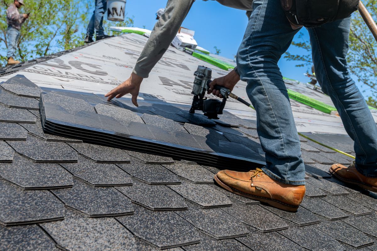 Roofer nailing architectural shingles